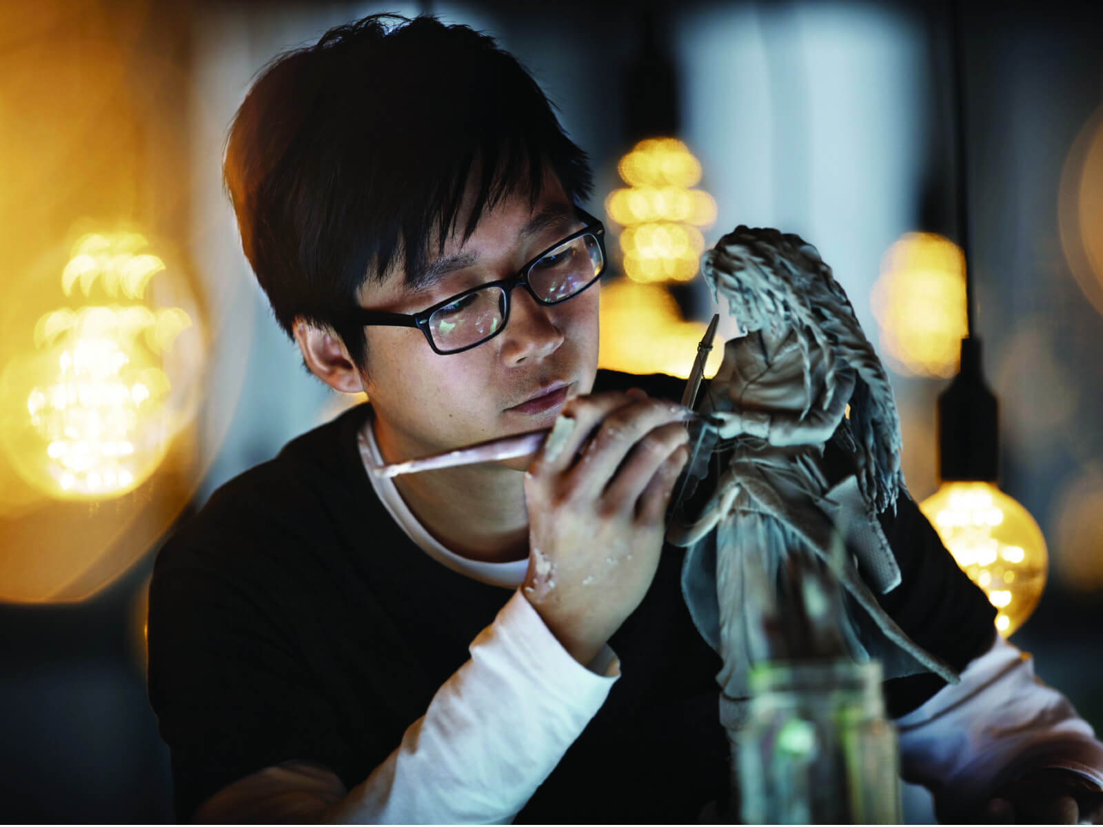Male student carefully sculpting a detailed female clay statue