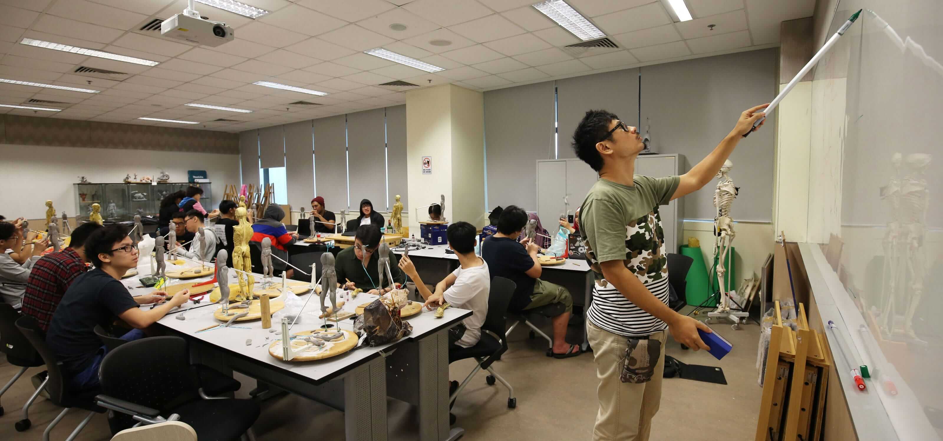 Students in a DigiPen (Singapore) sculpting class watch as an instructor writes on a whiteboard