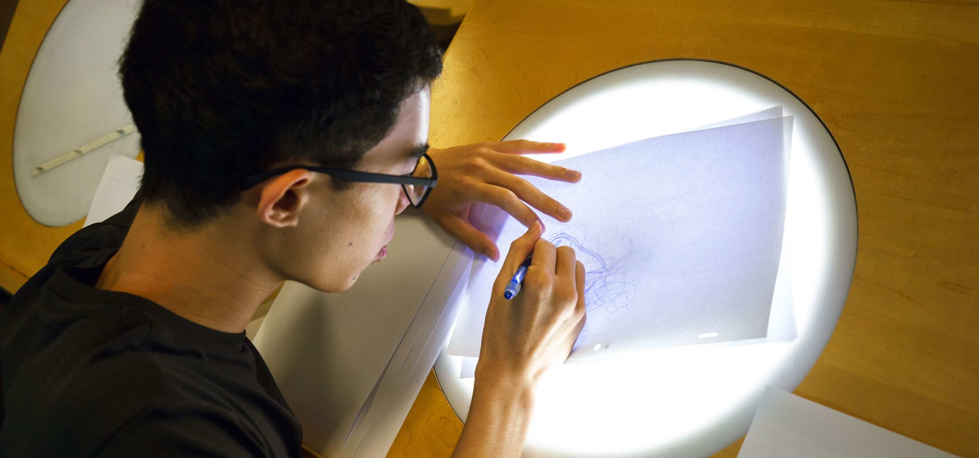 Over-the-shoulder shot of a DigiPen (Singapore) student drawing on an animation lightbox