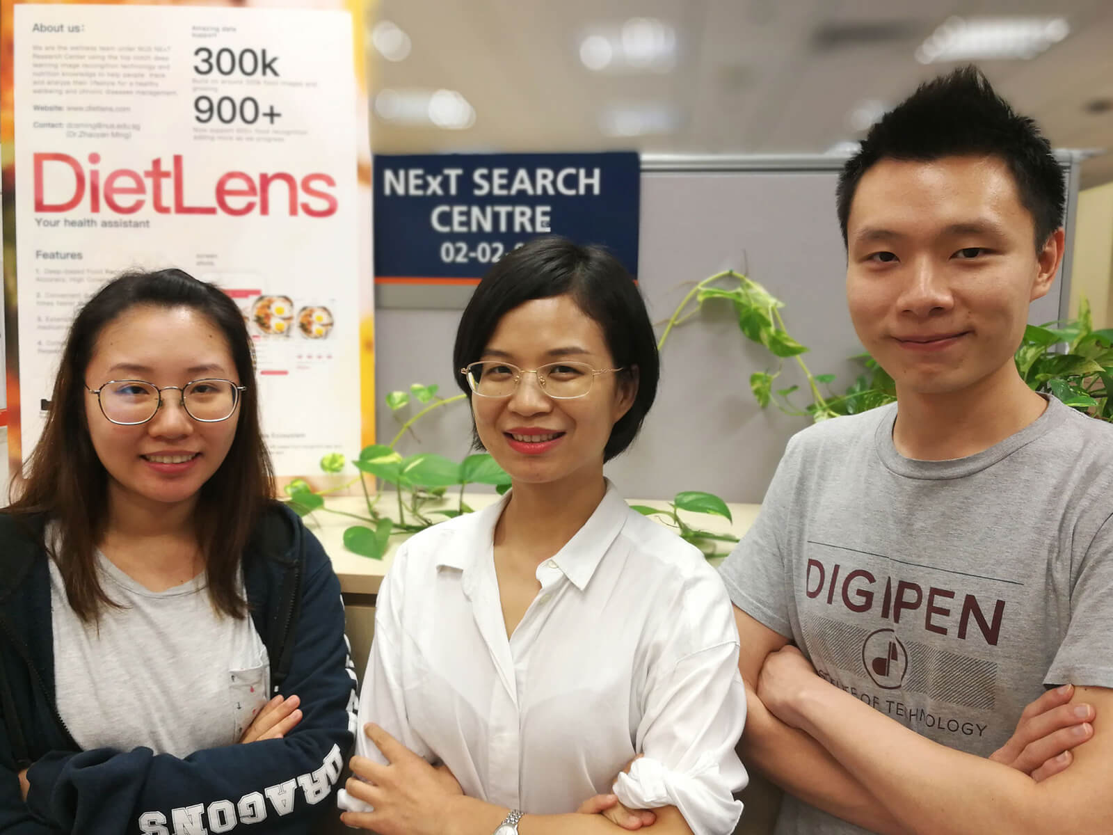 DigiPen (Singapore) alumni Irene Tan and Lim Sing Gee pose with a coworker in front of a DietLens banner.
