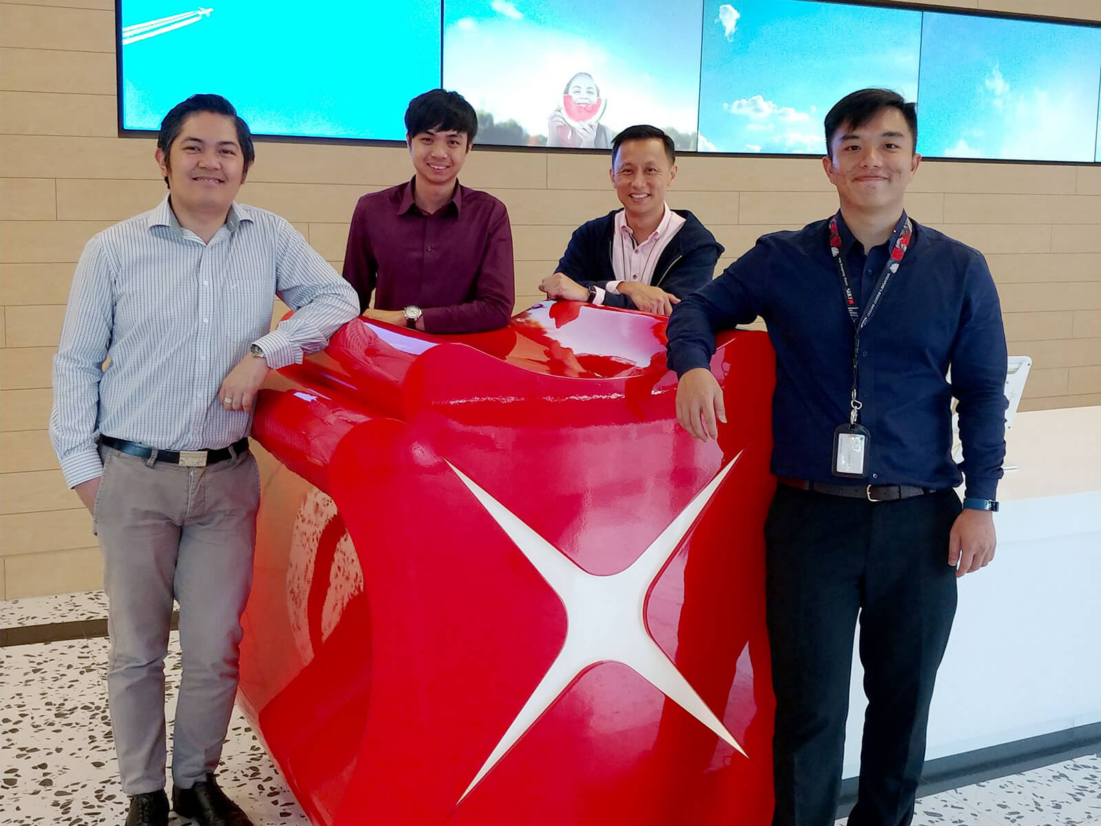 DigiPen Singapore alumni Izak Foong and Farris Chua pose with co-workers in DBS Bank lobby