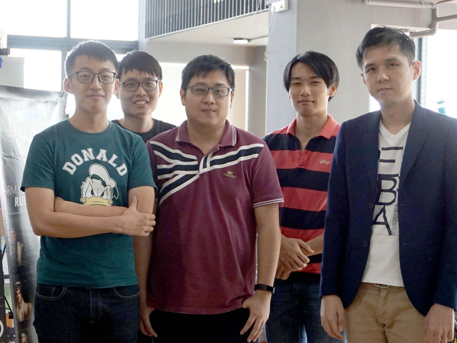 A group of DigiPen (Singapore) alumni pose next to a banner advertising the ORCA Integrated Business Operating System