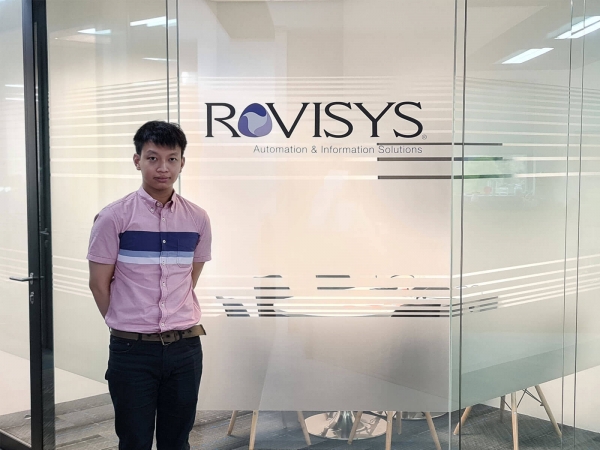 Jacky Chan standing in front of glass meeting room with Rovisys logo