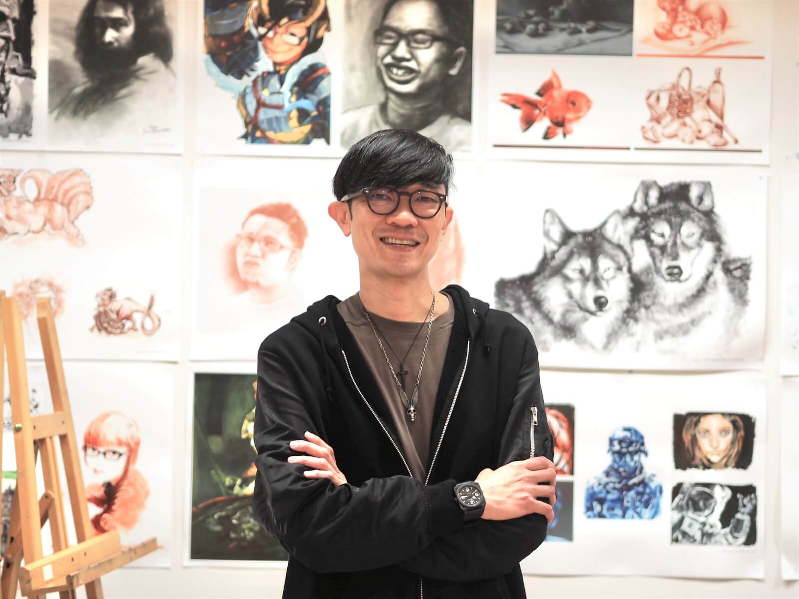 DigiPen Department Chair Dominic Chang stands in front of a wall full of student art work